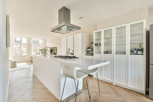 A sleek and contemporary kitchen featuring an open layout with white cabinetry, an island, and large windows for natural light. Ideal for modern living spaces.