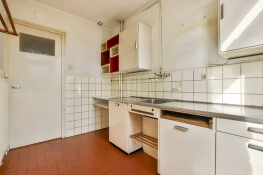 A clean and simple kitchen featuring white tiles and minimalist cabinetry. The warm tones create a cozy atmosphere, perfect for cooking.