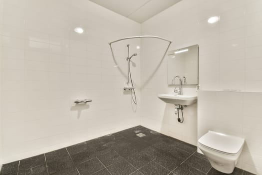 A sleek and minimalist bathroom featuring white tiles, a contemporary shower, sink, and toilet. The clean lines and spacious layout evoke a sense of tranquility.