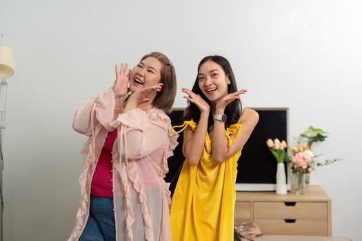 These two friends share a laugh, striking playful poses in fashionable outfits that highlight their joy and friendship in a stylish setting.
