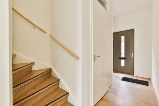 A stylish interior view showcasing a modern staircase and entrance. The design features clean lines, light colors, and minimalistic elements, enhancing the inviting atmosphere.
