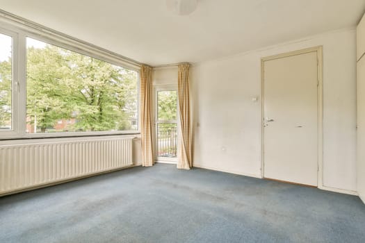 A bright room featuring large windows that allow natural light to fill the space, complemented by light-colored walls and simple decor.
