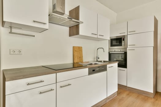 A spacious, modern kitchen featuring sleek white cabinetry, a stylish wooden countertop, and contemporary appliances for an elegant culinary experience.