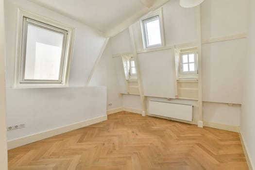 Bright, airy room featuring stylish triangular windows and a warm wooden floor, ideal for relaxation or work. The minimalist design enhances the spacious feel.