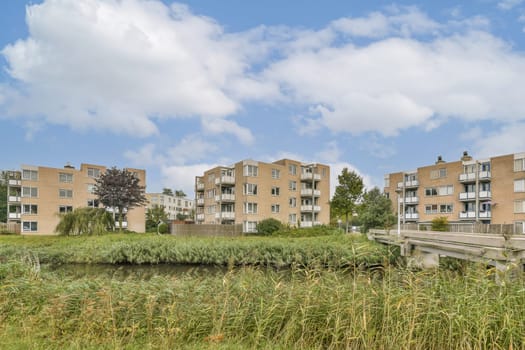 Contemporary apartment complexes surrounded by lush greenery and a calm waterway, showcasing an idyllic living environment amidst nature.
