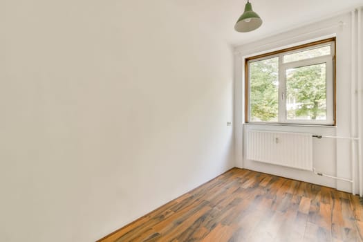A sparse interior featuring a window that lets in natural light, highlighting the wood floor and clean walls. Ideal for modern design inspiration.