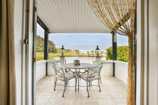An inviting outdoor patio featuring a round table and chairs, surrounded by lush greenery and decorative lanterns, perfect for relaxation and gatherings.