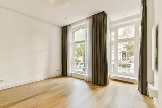 Elegant room featuring large windows, soft curtains, and warm wooden flooring, offering a bright and airy atmosphere for relaxation or creativity.