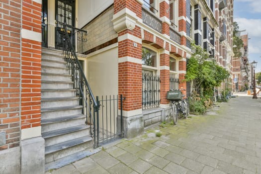 A picturesque view showcasing a charming brick building's entrance with well-designed stairs, a bicycle, and greenery lining the pathway. Ideal for urban architecture lovers.