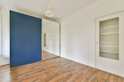 A stylish modern interior showcasing a blue accent wall and a large mirror, complemented by wooden flooring and minimalistic decor elements.