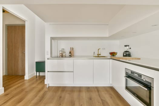 A contemporary kitchen featuring minimalist design elements, including a stylish countertop, elegant cabinetry, and natural wood flooring, creating a warm ambiance.