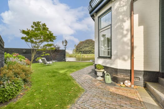 A serene garden featuring lush greenery and a charming brick pathway beside a contemporary home, perfect for outdoor relaxation and landscaping inspiration.
