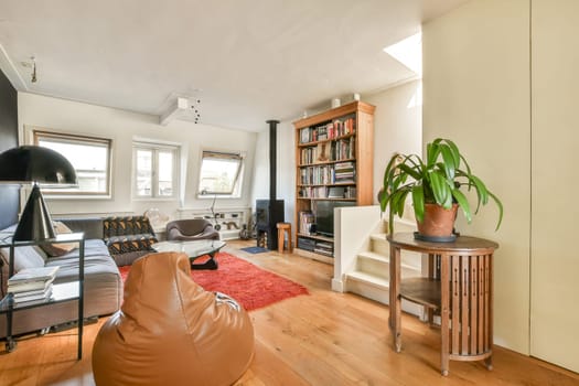 A stylish and inviting living room featuring a mix of modern furniture and natural light, accented by indoor plants and warm wooden flooring.
