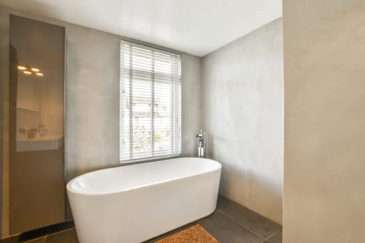 A sleek and stylish bathroom featuring a free-standing tub, large window, and contemporary design elements. The space emphasizes clean lines and natural light.