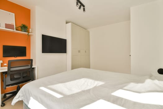 A sleek and stylish bedroom featuring a bed, desk, and wall-mounted television. Bright colors blend with natural light for a refreshing atmosphere.