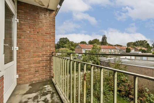 A serene balcony view featuring lush greenery and residential homes under a partly cloudy sky, highlighting the beauty of suburban life.