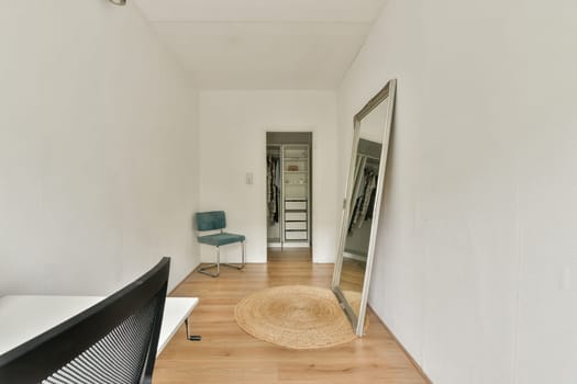 A simple yet elegant room showcasing a large mirror, a chair, and wooden flooring, highlighting clean lines and minimal decor for an airy feel.