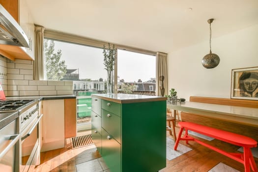 A bright and contemporary kitchen featuring a striking green island, large windows offering natural light, and stylish furnishings that create an inviting atmosphere.