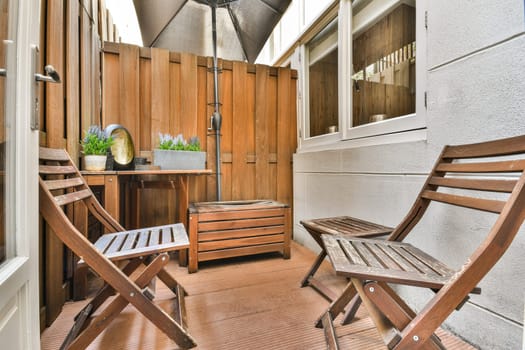 An inviting outdoor patio featuring wooden chairs, a small table, and potted plants, perfect for relaxation and enjoying the fresh air.