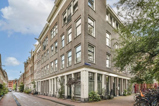 A beautifully designed modern building showcases a unique architectural style at the corner of a city street, surrounded by greenery and bicycles.