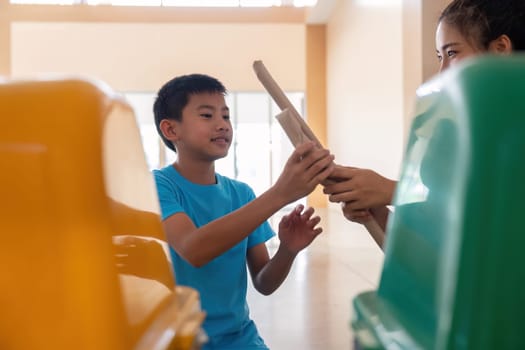 A mother teaches her young son the importance of recycling as they sort paper waste together in a community space, promoting sustainable habits for a better future.