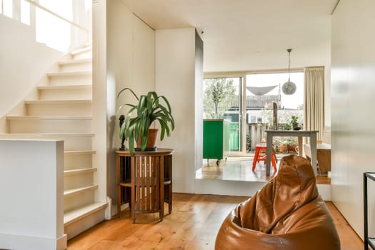 A stylish modern indoor living space featuring natural light, wooden flooring, and decorative plants that enhance the cozy ambiance.