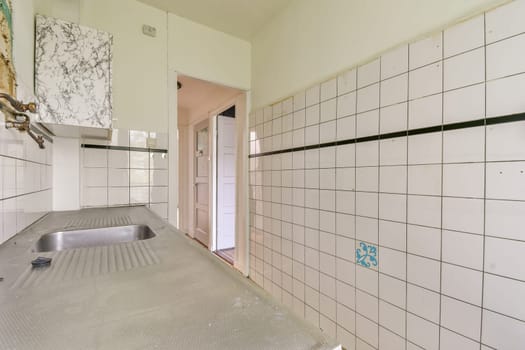 A contemporary kitchen showcasing stainless steel surfaces and minimalistic design, featuring tiled walls and clean lines.