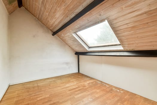 A cozy attic space featuring wooden beams, a skylight, and a warm-toned floor, ideal for creative or leisure activities.