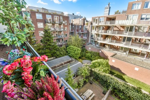 A colorful scene featuring a flower-filled balcony overlooking residential buildings and lush greenery in an urban setting, showcasing a harmonious blend of nature and architecture.