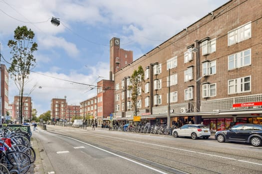 A vibrant urban street showcasing parked bicycles, charming architecture, and pedestrians under a partly cloudy sky, embodying city life.