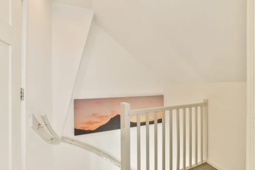 A sleek and modern staircase leads upwards, featuring a minimalistic design with white walls and a framed art piece for visual interest.