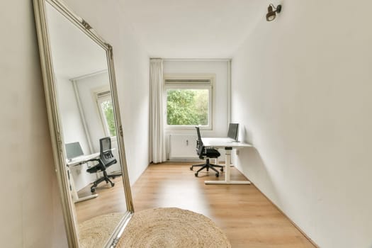 A minimalist home office space featuring a large mirror and a simple desk setup. Natural light streams in through a window, enhancing the calm atmosphere.