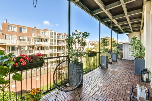 A vibrant balcony adorned with flowers and plants, offering a bright view of urban buildings under clear blue skies, enhancing outdoor relaxation.