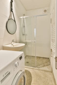 Featuring a sleek design, this space combines a shower area, sink, and a washing machine, ensuring practicality and style in a modern bathroom setup.