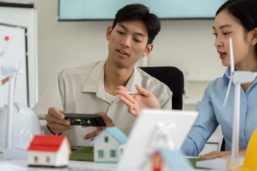Two young professionals exchange ideas and technologies to enhance sustainable construction practices, demonstrating innovative tools and commitment to ESG goals.