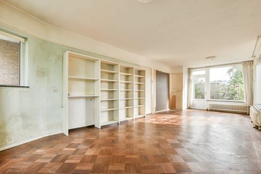 A vacant room featuring large windows that allow natural light to flood in, highlighting the wooden floor and white walls. Perfect for renovation or new decor.