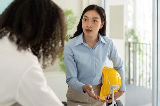 In a focused discussion, a young female professional articulates the importance of safety regulations for sustainable building projects to her colleagues.