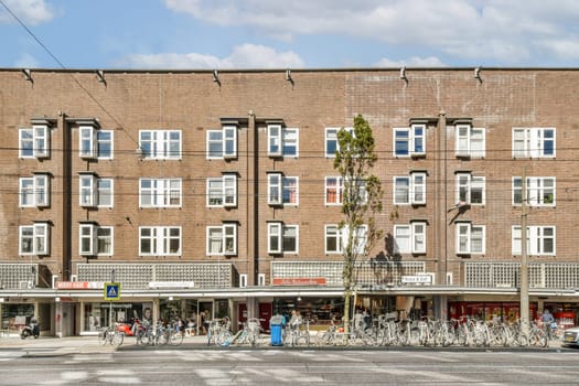 A striking modern building facade featuring numerous windows, surrounded by bicycles and pedestrians in an urban setting. A blend of functionality and design.