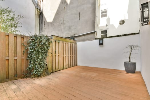 A modern outdoor area featuring wooden decking, a boundary fence, and decorative plants, creating a serene and inviting atmosphere.