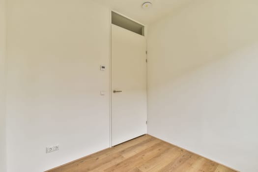 A minimalist interior space featuring a white door and light wood flooring, creating a clean and modern aesthetic in the room.
