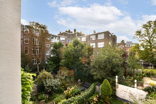 A vibrant urban garden filled with various plants and trees, surrounded by residential buildings, creating a serene escape in the city.