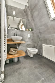 A contemporary bathroom featuring sleek gray tiles, a stylish sink, and wooden shelving, creating a clean and inviting space for relaxation.