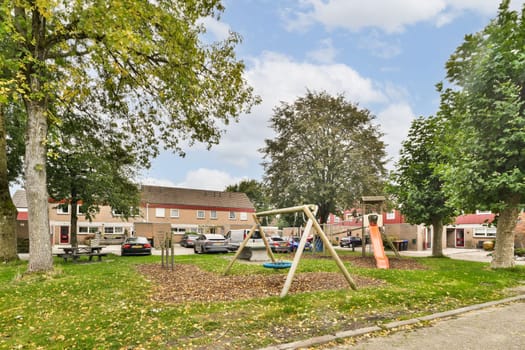 A vibrant playground with swings and slides nestled amongst lush green trees, providing a perfect recreational space for children in a residential area.