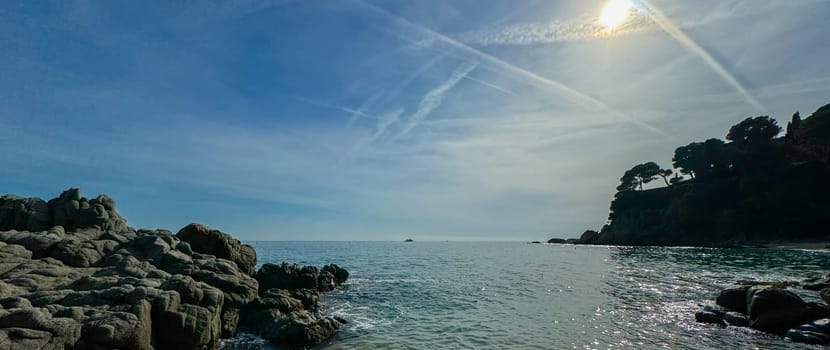 A breathtaking beach landscape in Lloret de Mar, Spain, featuring massive rocks and cliffs along the coastline. The natural beauty of the area is perfect for outdoor and travel. Banner