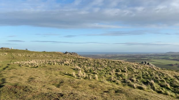 View from the summit of Traprain Law in East Lothian, Scotland, overlooking the surrounding countryside and the sea, under a partly cloudy sky - Nr Haddington, UK