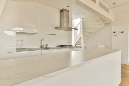 A sleek and contemporary kitchen featuring white cabinetry, a marble countertop, and minimalistic design elements. Ideal for modern living spaces.