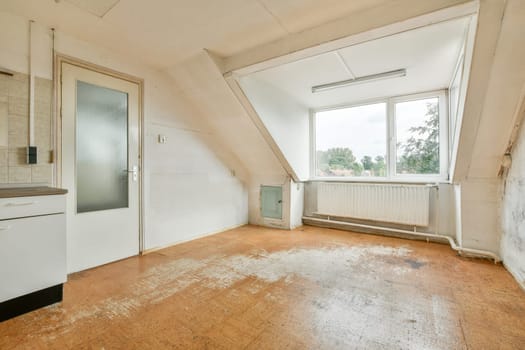 Bright and airy attic room featuring a large window, minimal furnishings, and unfinished flooring. Ideal for a creative workspace or cozy retreat.