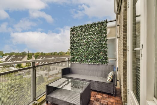 A stylish balcony featuring a sleek sofa set and vibrant greenery, perfect for relaxation and outdoor living in an urban environment.