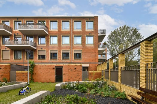 A contemporary residential structure featuring an attractive brick facade, balconies, and a well-maintained garden area, promoting a pleasant living environment.