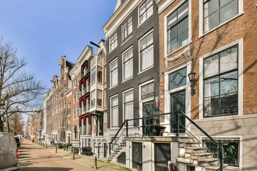 A scenic view of a picturesque Amsterdam street lined with unique, colorful buildings and lush trees. A perfect representation of urban architecture and culture.